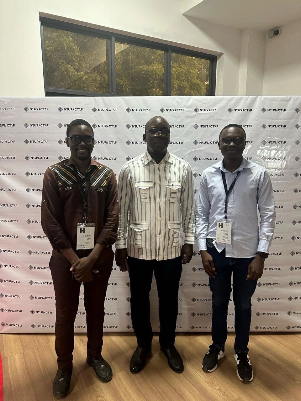 The Miabé IA team standing either side of the former Minister of Education, in front of the Neuractif press wall.